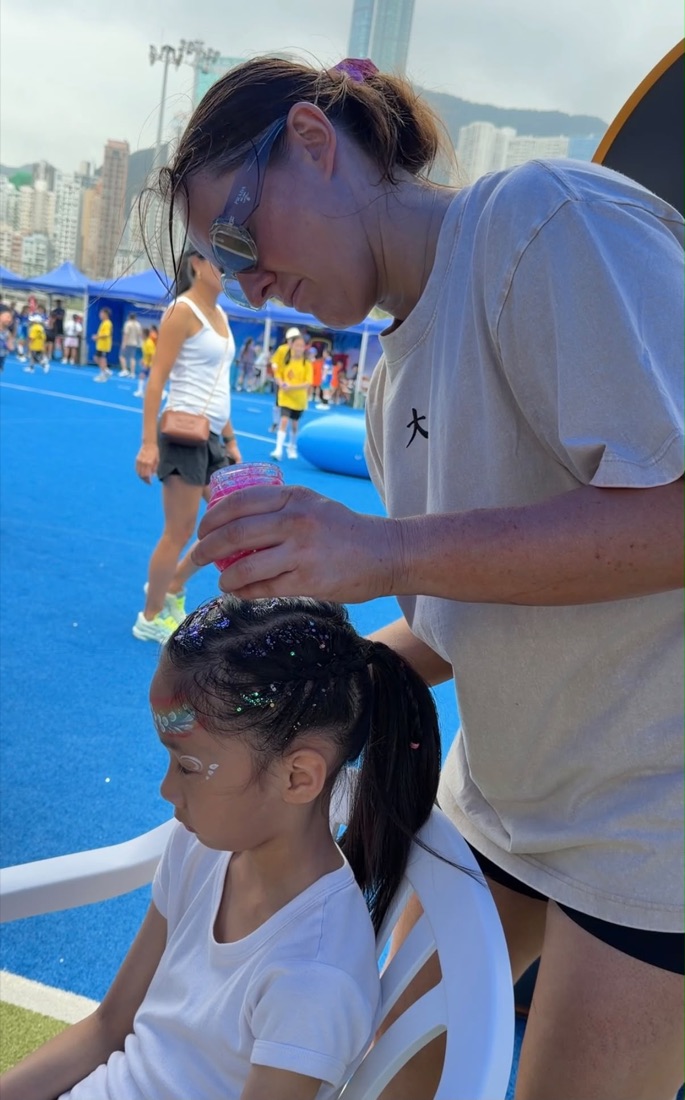 A Braid Locker team member adding pink glitter to a girl's braided hair at the Hong Kong pop-up